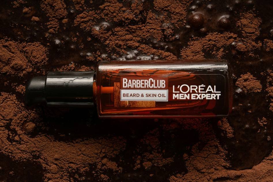 Man applying beard oil with a focused expression in a rustic bathroom setting