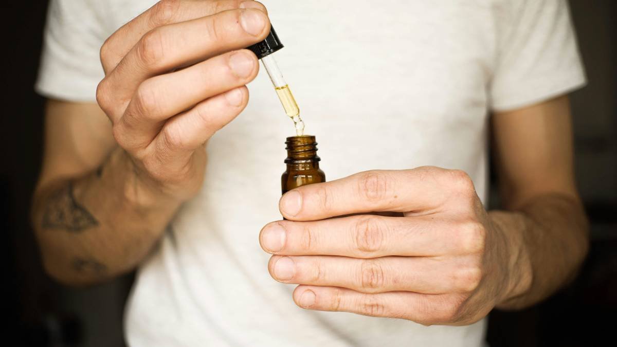 Bottle of natural beard oil blend with amber glass and pipette on wooden surface